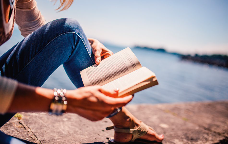 Kobieta czytająca książkę nad wodą